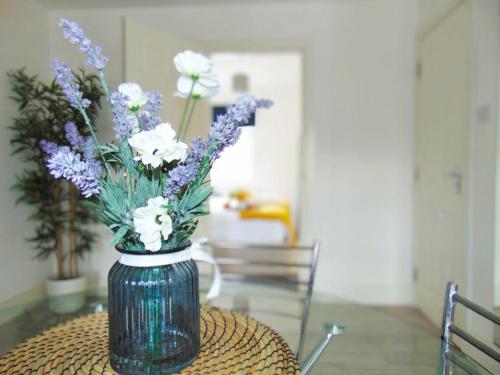 a vase filled with purple and white flowers on a table at Luxury 2 Bed, 2 Bath Apartment in Central Watford in Watford