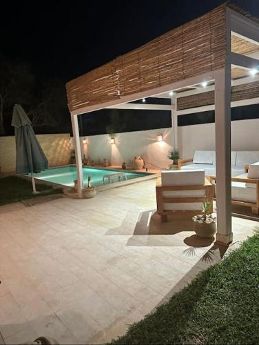 a patio with a swimming pool at night at Dar Douja à Chaffar / Ton chez-toi près de la plage in Nakta