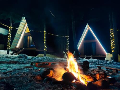 Un feu brûle dans la neige avec des feux de Noël dans l'établissement Bude Mestia cottages, à Mestia