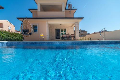 a villa with a swimming pool in front of a house at Vila Orchidee in Poreč