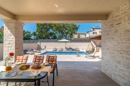 a patio with a table and chairs next to a pool at Vila Orchidee in Poreč