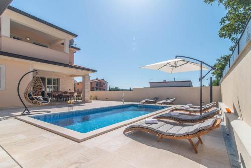 a swimming pool with lounge chairs and a house at Vila Orchidee in Poreč