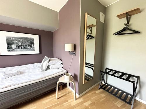 a small bedroom with a bed and a mirror at Linnéplatsens Hotell & Vandrarhem in Gothenburg