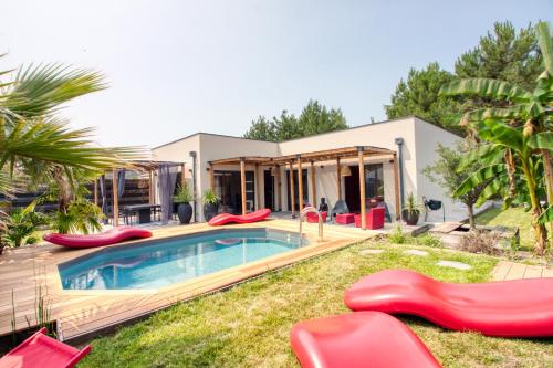 une maison avec une piscine et des chaises de jardin rouges dans l'établissement Villa Meli - Le Porge : la plage, Lège-Cap Ferret et Lacanau à 10 minutes, à Le Porge
