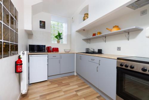 Il comprend une cuisine avec des placards blancs et du parquet. dans l'établissement La Vie en Rouge - Parking gratuit, à Carcassonne