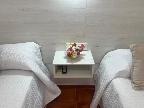 a bedroom with two beds and a table with flowers on it at Hostal Los Mellizos in Conil de la Frontera