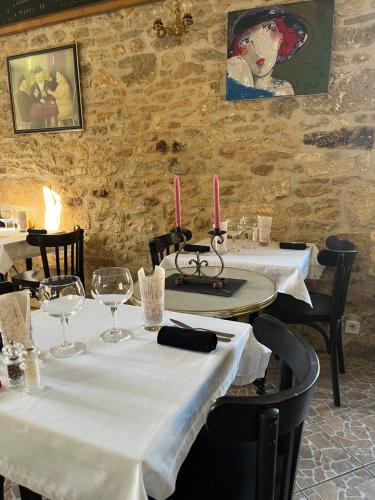 un restaurant avec deux tables avec des nappes blanches et des bougies dans l'établissement Hôtellerie de l'Abbaye Saint Amand, à Saint-Amand-de-Coly