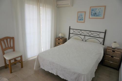 - une chambre avec un lit blanc et une chaise dans l'établissement Bungalow PUEBLO MAR en Els Poblets., à Dénia