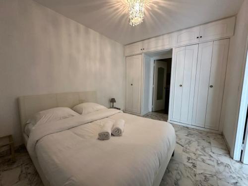 une chambre avec un grand lit blanc avec un lustre dans l'établissement C062 Appart fonctionne Proche du centre Cannes, à Cannes