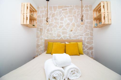アルブフェイラにあるAmelie Old Town Apartmentのベッドの上に黄色い枕とタオルが置かれた寝室