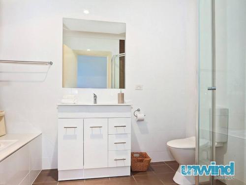 Block Escape - Ocean View Apartment No 1 في فيكتور هاربور: حمام أبيض مع حوض ومرحاض