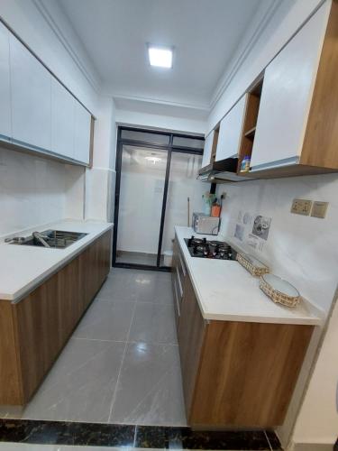 a kitchen with white counter tops and wooden cabinets at Luxury Apartment Lavington in Mutomo