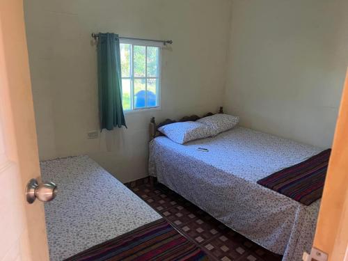 2 camas en una habitación pequeña con ventana en Rancho Agua Fria casa, en Usulután
