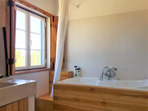 een badkamer met een bad en een raam bij GR ALENTEJO HILLS Nature & Tranquility! Beach 35m in Grândola