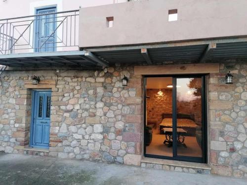 a stone building with a balcony and a glass door at KTHMA "Ν" Πέτρινη Μεζονέτα in Ververáton
