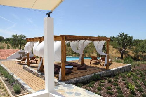 een houten terras met een prieel naast een zwembad bij GR ALENTEJO HILLS Nature & Tranquility! Beach 35m in Grândola