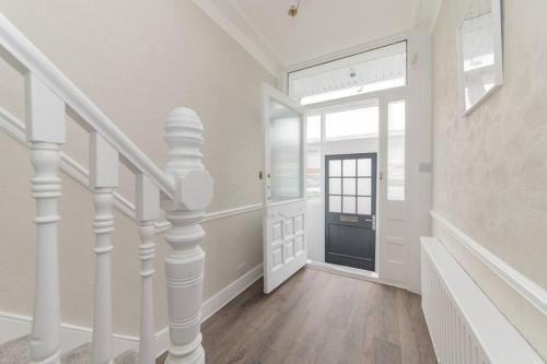 pasillo blanco con escalera y puerta en Stylish & Spacious 3-Bed House, Parking and Garden, en Finchley