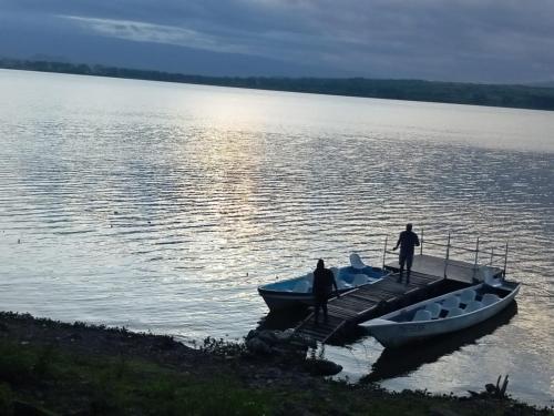two people on a dock with two boats on the water at Elsamere Lodge Naivasha in Naivasha
