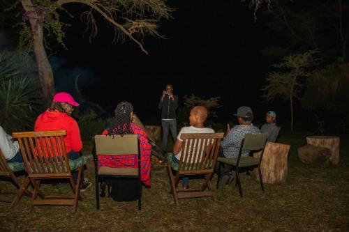 eine Gruppe von Menschen, die nachts auf Gartenstühlen sitzen in der Unterkunft Elsamere Lodge Naivasha in Naivasha