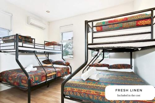 a room with three bunk beds in it at Block Escape No 5 - Penthouse Balcony Wi-fi in Victor Harbor