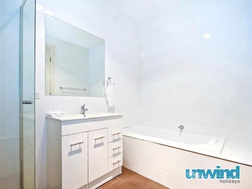 a white bathroom with a sink and a mirror at Block Escape No 5 - Penthouse Balcony Wi-fi in Victor Harbor