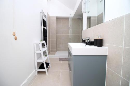 a white bathroom with a sink and a mirror at Heart of Bath: Kingsmead Apartment in Bath