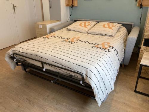 un lit dans une chambre avec une couverture orange et blanche dans l'établissement Le Refuge / pied-à-terre pragmatique, à Dijon