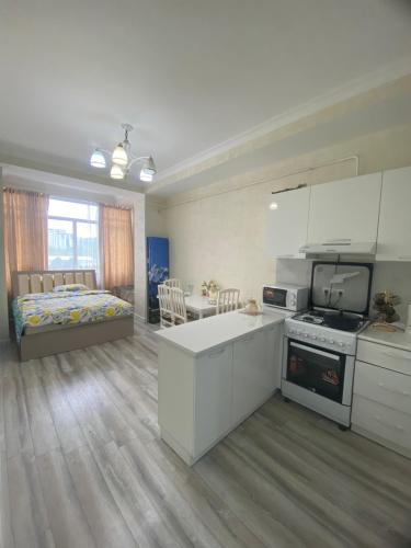 Kojomkul في بيشكيك: مطبخ وغرفة معيشة مع سرير في غرفة