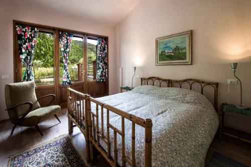 a bedroom with a bed and a chair and a window at Fattoria La Tavernuzza in Grassina