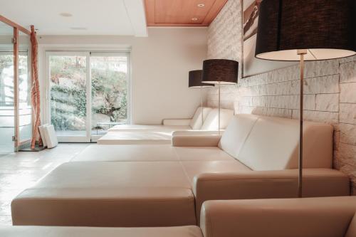 a row of white couches in a room with windows at Residence Hotel Alpinum in Campo Tures