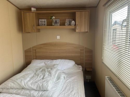 ein Schlafzimmer mit einem Bett mit einem Kopfteil aus Holz in der Unterkunft 3 Bed Caravan Lido Beach in Prestatyn
