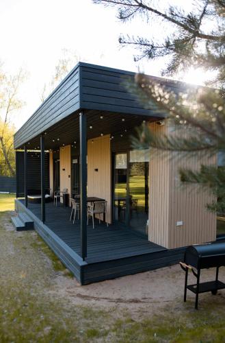 a black house with a deck with tables and chairs at Chill Hill Kalviai in Kalviai