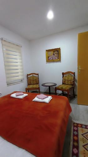 a bedroom with a large red bed with two chairs at Apartman Orhan in Mostar