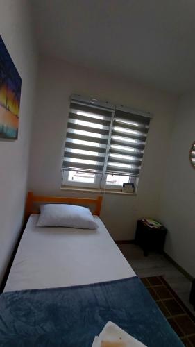 a bedroom with a bed and a window with blinds at Apartman Orhan in Mostar