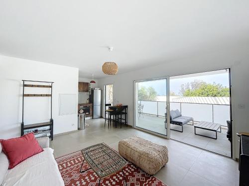 un salon avec un canapé et une grande fenêtre dans l'établissement T2 dans résidence avec piscine, à Calvi