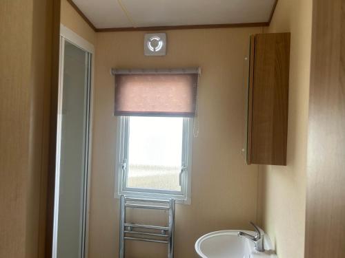 ein Bad mit einem Waschbecken und einem Fenster in der Unterkunft 3 Bed Caravan Lido Beach in Prestatyn
