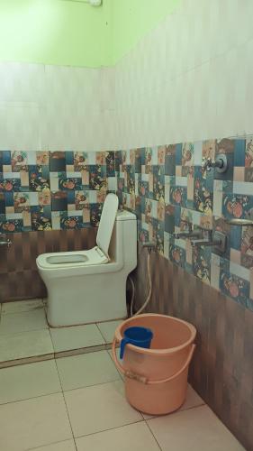 a bathroom with a toilet and a bucket in it at Hotel Srimanta sankardev in Majuli