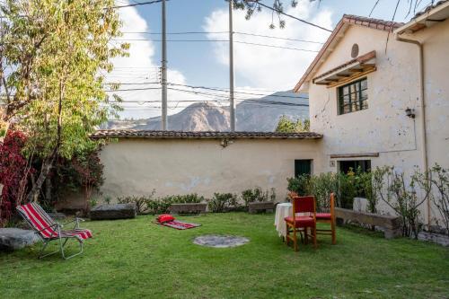 a yard with chairs and a house with mountains in the background at Hospedaje La Florida in Urubamba