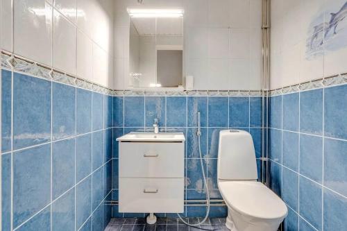 La salle de bains est pourvue de carrelage bleu, de toilettes et d'un lavabo. dans l'établissement Upea saunallinen kolmio, à Nokia