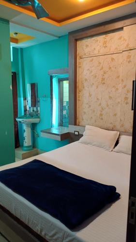 a bedroom with a large bed with a blue wall at Hotel Srimanta sankardev in Majuli