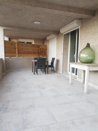 un patio avec une table, des chaises et un bol vert dans l'établissement Maison T2 500m de la plage, à Poggio-Mezzana