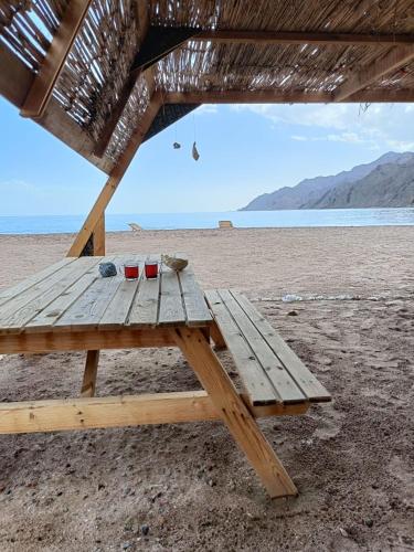a wooden picnic table sitting on the beach at Sea sound Camp in Nuweiba‘ el Muzeinah