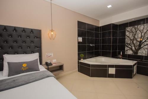 um quarto com uma cama e uma banheira em Hotel Perlatto em Bello