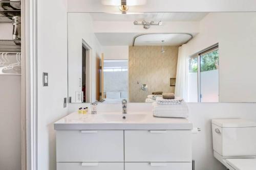 een witte badkamer met een wastafel en een spiegel bij Historic Desert Star in Palm Springs