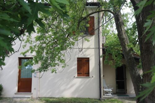 ein weißes Haus mit Holztüren und einem Baum in der Unterkunft Holiday Home Giaron in Rosolina