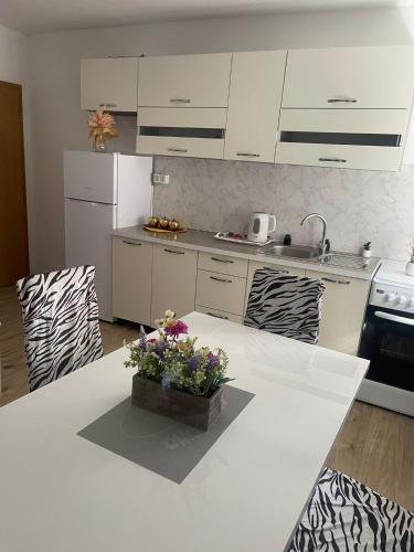 a white kitchen with a table with flowers on it at Apartmani Žuti in Neum