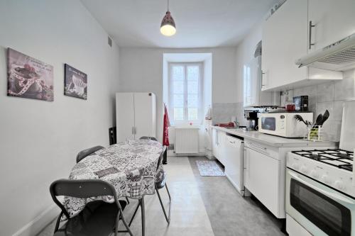 une cuisine blanche avec une table et des chaises dans l'établissement Appartement à Luchon, à Luchon