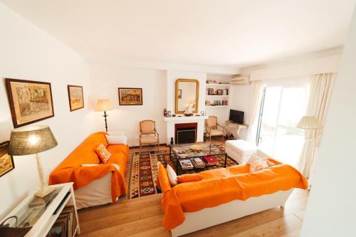 een woonkamer met 2 oranje banken en een open haard bij Andalusian beach haven villa in El Puerto de Santa María
