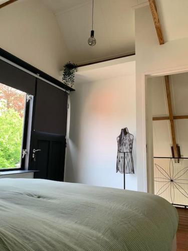 a bedroom with a bed and a dress hanging on the wall at Bosrijke vrijstaande woning in Heiloo
