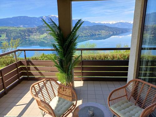 d'un balcon avec deux chaises et un palmier. dans l'établissement Panoramasuite am Millstättersee, à Dellach